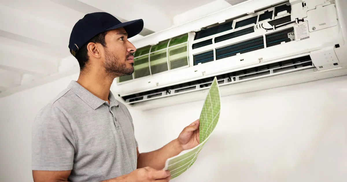 A Rapid Response team member is inspecting an indoor AC unit and preparing to replace the air filter for cleaner airflow