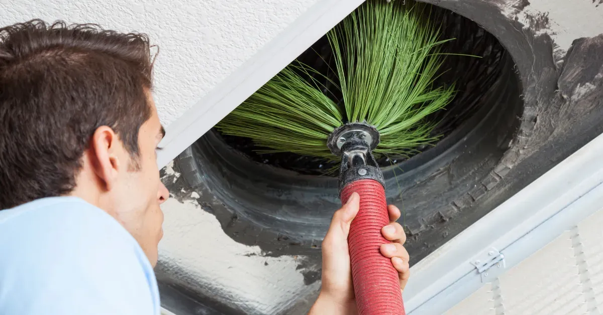 Technician cleaning air ducts using a rotating brush tool