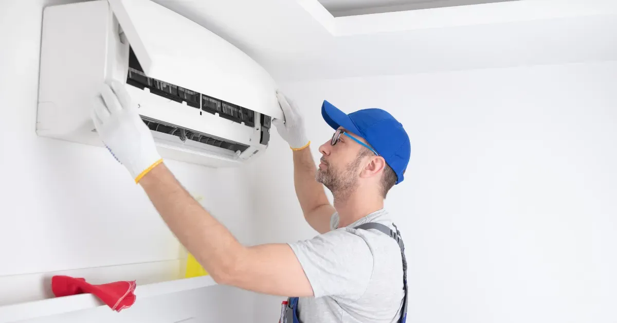 Technician opening an air conditioner panel to inspect and clean internal components