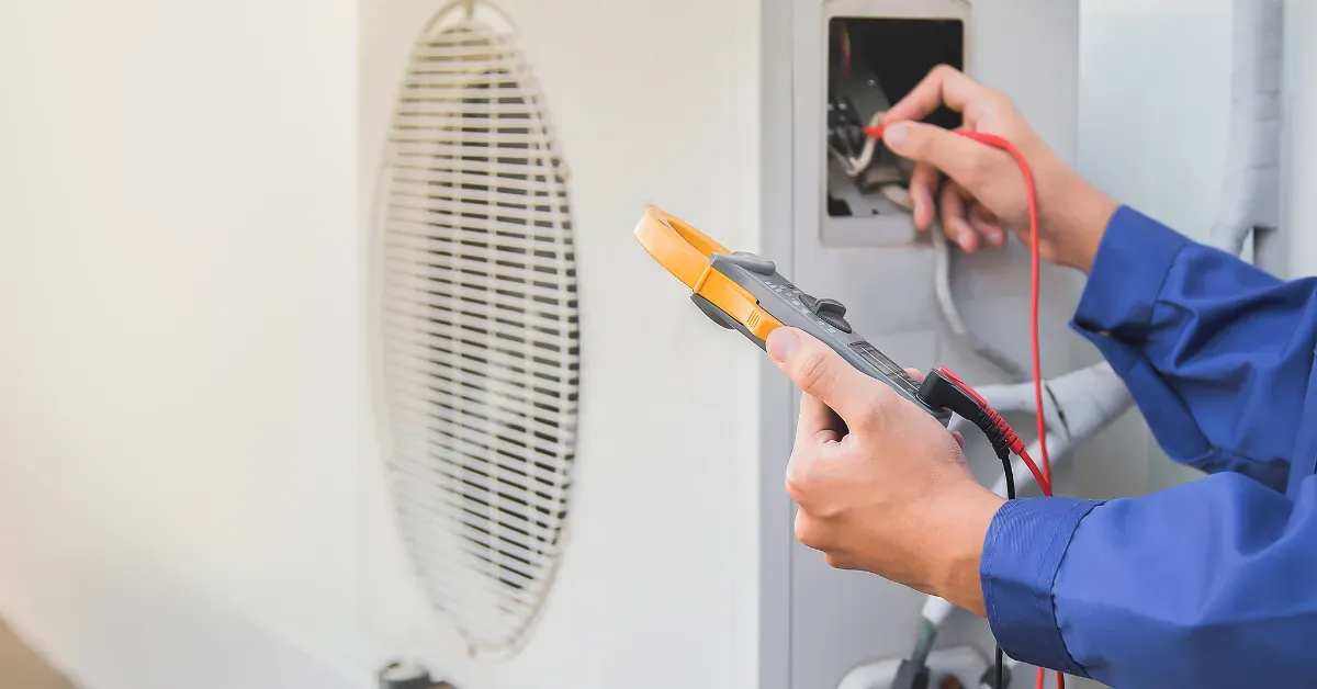 A technician using a multimeter to test and diagnose an outdoor air conditioning unit