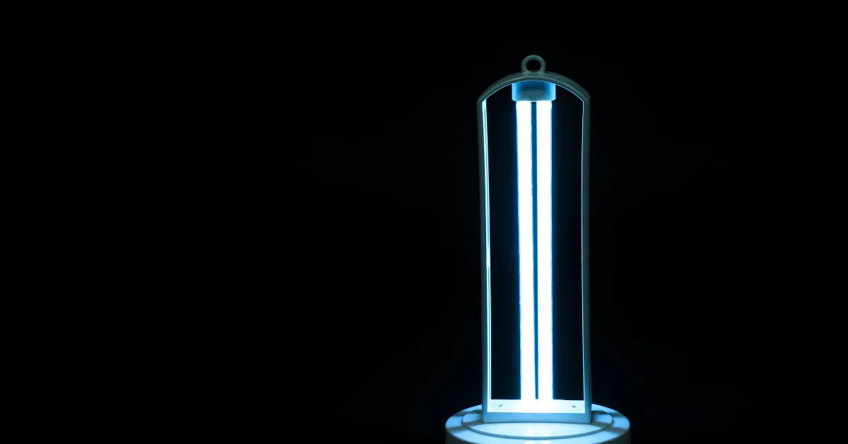 A portable UV air purifier glows bright in a dark room