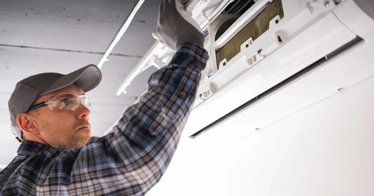 Specialist carefully accessing the internal housing of a wall-mounted AC system to verify cleanliness