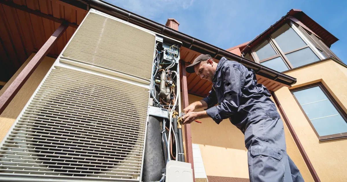 A technician repairing an outdoor air conditioning unit at a residential home