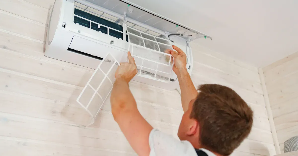 Rapid Response technician removing dusty air filters from a wall-mounted AC unit
